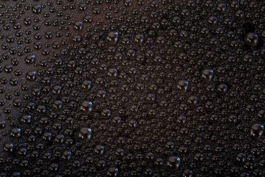 many small water drops on the black surface of cellphone hydriphobic coated glass screen, close-up with selective focus and visible subpixel rgb triads
