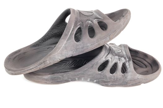 pair of used cheap black soft rubber slippers with signs od friction wear isolated on white background.