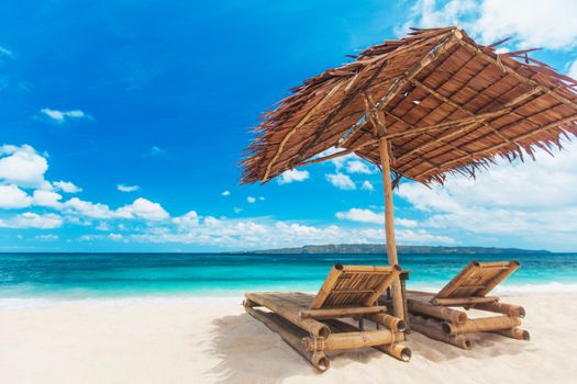 Beach chairs and umbrella on a beautiful tropical sea beach, view with copy space