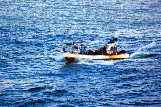 A small fishing boat heads out to sea in choppy waters
