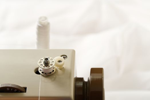 hands of a seamstress winding thread from a spool to a bobbin, close-up