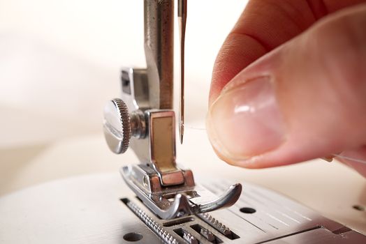 woman threading a needle on a sewing machine. close up, selective focus