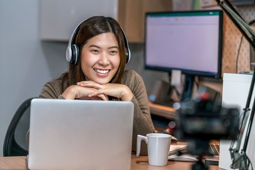 Asian business woman using technology laptop and working from home in home office, freelance and entrepreneur, camera taking video of vlogger or influence Live, social distance and self responsibility