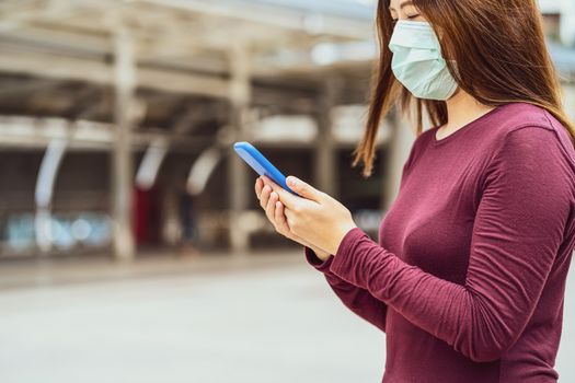 Closeup Asian woman hand using smart mobile phone with safety medical face mask for prevent Coronavirus or Covid19 Outbreak when travel to work in business downtown, Health care and infection concept