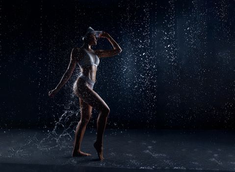 Beautiful athletic caucasian girl with a perfect figure is standing under the water. Fitness woman in a spray of water. Sports freshness. concept Classic dark blue color background