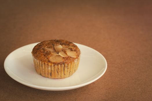 Delicious banana cup cake on white dish and wooden table with copy space. Homemade bakery.