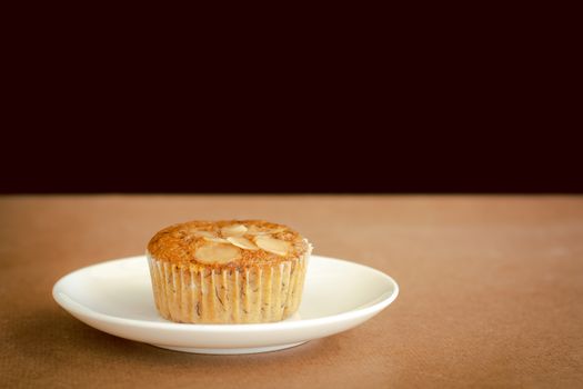 Delicious banana cup cake on white dish and wooden table with copy space. Homemade bakery.