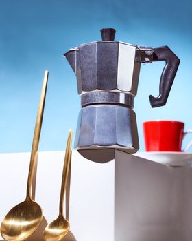 Geyser coffee maker, two golden spoons and red cup for coffee shop stand on a white cube. High quality photo