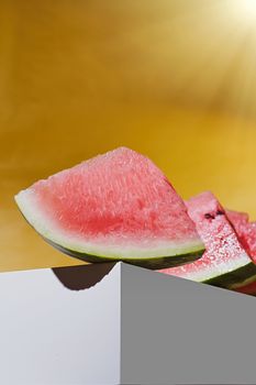 slices of ripe watermelon lie on the white cube. yellow background. High quality photo