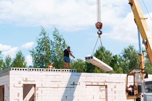 Builder worker installing concrete floor slab panel at building construction site. Second floor house concrete floor slab installation