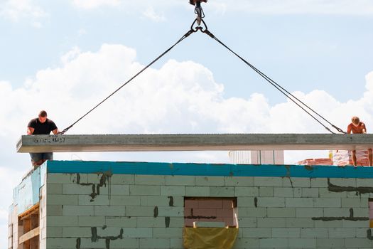 Builder worker installing concrete floor slab panel at building construction site. Second floor house concrete floor slab installation