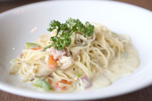 Spaghetti with mushroom and ham white sauce on wood background