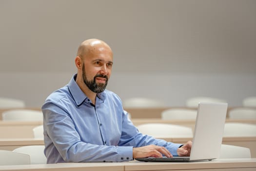 Young man on a university lecture working on a white laptop