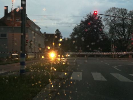 Closed barriers of a railroadcrossing at dusk in the rain