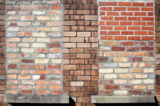 Old large weathered distressed red brick wall with bricked up windows texture background stock photo