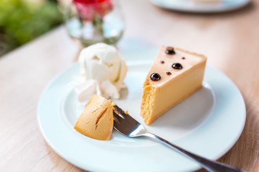 A piece of delicious caramel cheesecake served with ice cream and flowers on the table