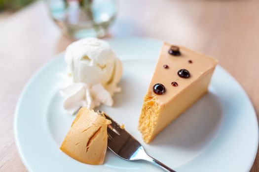 A piece of delicious caramel cheesecake served with ice cream and flowers on the table