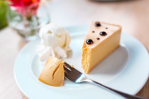 A piece of delicious caramel cheesecake served with ice cream and flowers on the table