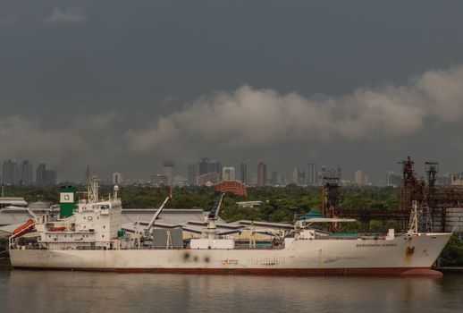 Bangkok, Thailand - Jun 17, 2020 : Cargo ships are floating over the Chaopraya river. They are waiting to be docked at pier.