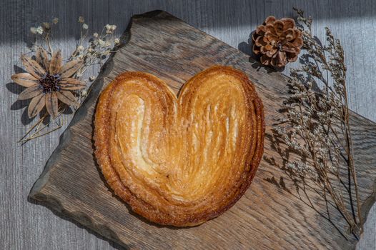 Butter Palmier bread, French pastry in palm leaf or a butterfly shape sometime look like pig's ear or elephant ear on rustic wooden board. Selective focus.