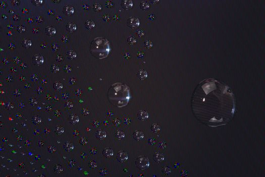 many small water drops on the surface of cellphone hydriphobic coated glass screen, close-up with selective focus and visible subpixel rgb triads