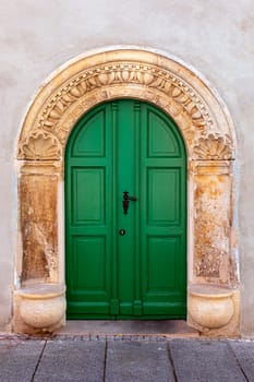 Green door inserted into an old Arch framed with Ornament



