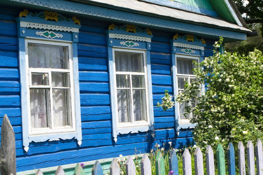 Ornamental carved windows and frames. Vintage rural house in Belarus. Traditional national folk style in wooden architecture. Blue and white