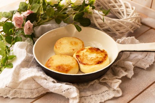 Baked fried cottage cheese pancakes in a white vintage pan, shabby table