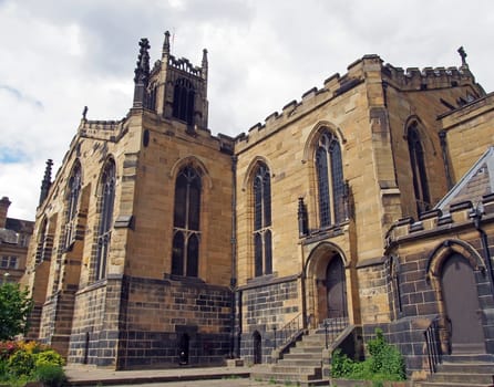 view of the clock tower and building of the historic saint peters parish church in the center of huddersfield against a cloudy sky