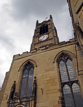 view of the clock tower and building of the historic saint peters parish church in the center of huddersfield against a cloudy sky