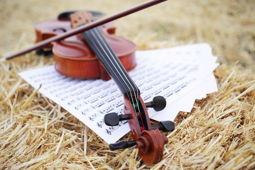 One violin and bow placed on a pile of straw in the field. Music Violin training. Fiddlestick, performing. Concept, baroque. Musical, fiddle.