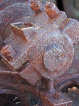 a close up of an axle bolts and wheel on old rusted abandoned industrial machinery