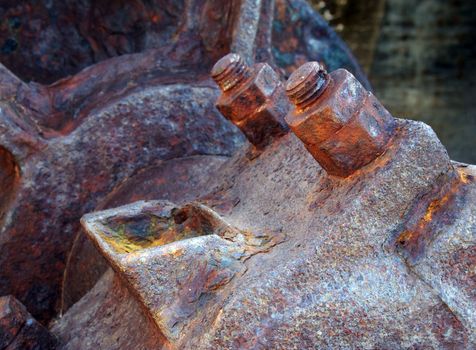 a close up of an axle bolts and wheel on old rusted abandoned industrial machinery