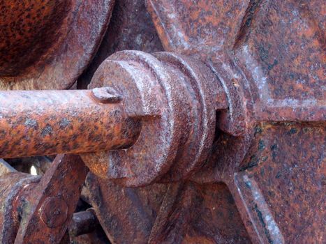 close up of an axle and wheel on old rusted abandoned industrial machinery