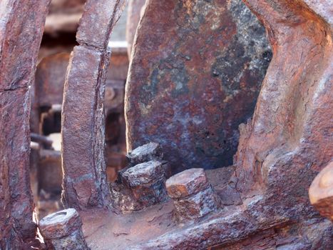 a close up of rusted iron wheels and gears with bolts on old corroded machinery