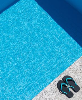 Flip flops on the edge of a pool. Copy space. Top view.