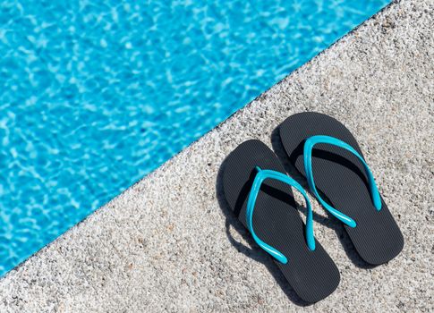 Close-up of a pair of flip-flops on the edge of a pool. Copy space. Top view.