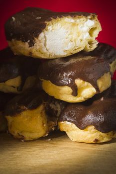 Eclairs with chocolate icing on a wooden table