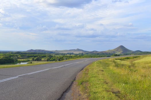 summer landscape with road, mountain and blue sky with clouds