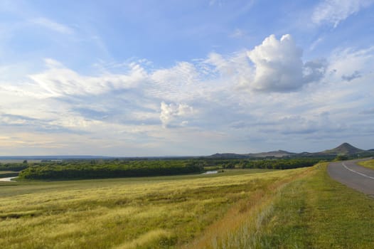 summer landscape with road, mountain and blue sky with clouds