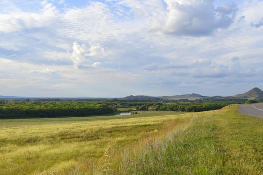 summer landscape with road, mountain and blue sky with clouds