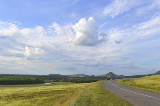 summer landscape with road, mountain and blue sky with clouds