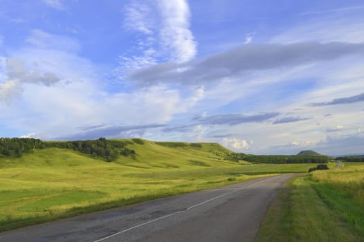 summer landscape with road, mountain and blue sky with clouds