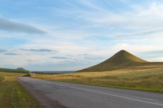 summer landscape with road, mountain and blue sky with clouds