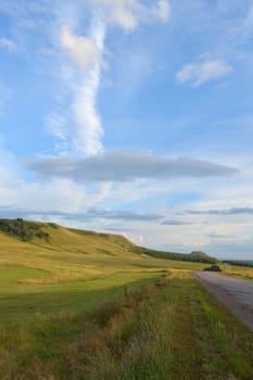 summer landscape with road, mountain and blue sky with clouds