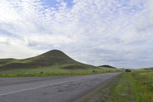 summer landscape with road, mountain and blue sky with clouds