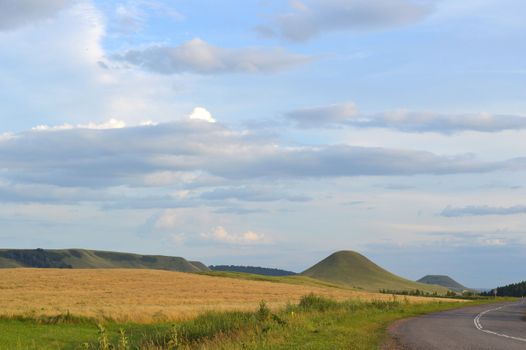 summer landscape with road, mountain and blue sky with clouds