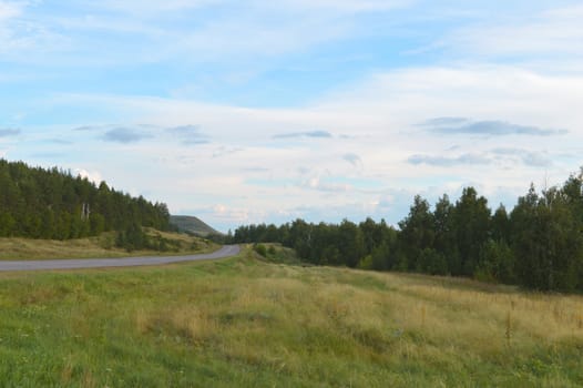 summer landscape with road, mountain and blue sky with clouds