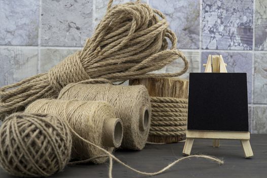 Assorted balls of hemp twine and string with skeins of rope and slate chalkboard in a close up rustic still life
