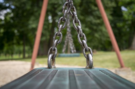 Close up detail of the chain attached to the seat on a playground swing in a low angle view